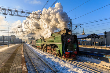 old black steam locomotive in Russia in the winter on the background of the Moscow railway station
