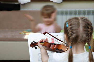 Mała dziewczynka gra na skrzypcach z nut. - obrazy, fototapety, plakaty