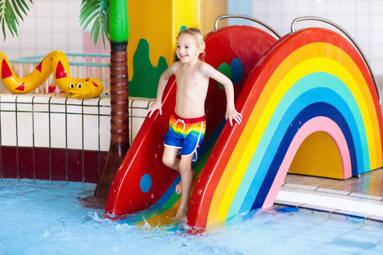 Child on swimming pool slide. Kids swim. Water fun