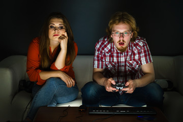 Woman is bored while man playing games
