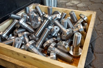 Bolts in a wooden box in the warehouse after turning and milling.