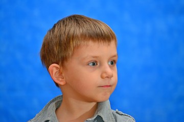 Boy in the studio on a blue background looking out into the distance