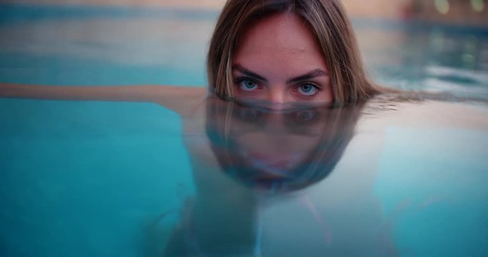 Young woman with blue eyes floating in swimming pool