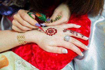 Henna design tattoo. Women applying roses henna tattoo on women hands. Woman draws mehendi on the...