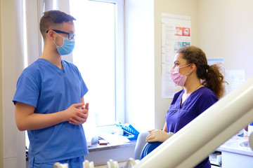 Fototapeta premium Handsome male dentist speaks with a female assistant at a clinic.