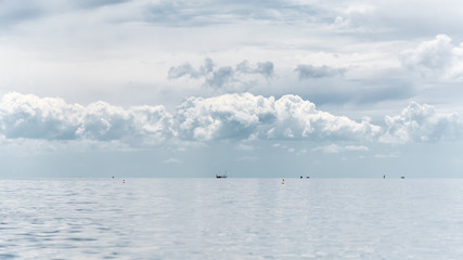 Morning seascape - cloudy sky above a quiet sea, buoys and ships in the distance, banner 16x9 format