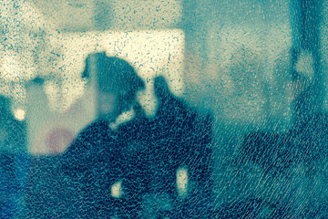 Blurred silhouettes of people behind broken glass. Fine mesh of cracks. Creative background. Female...