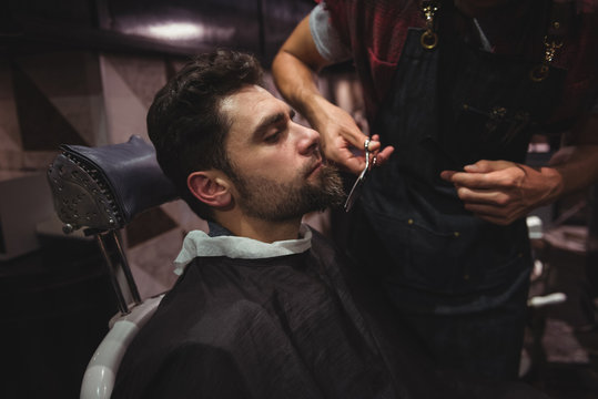 Man getting his beard trimmed with scissor