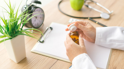 Female doctor holding unlabeled bottle of various pills and medication