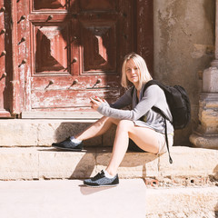 Traveller female watching the city map on the phone and sitting on the steps of the old church in Lisbon . Young pretty girl, sunrise time, happy face woman, cute, attractive.