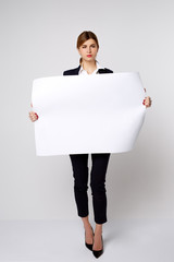 growth portrait of a girl in a business suit and white shirt big white sheet of paper on a white background