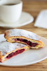 slices of strudel from puff pastry with a cup of tea on a wooden table