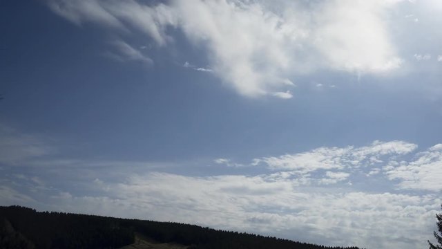 4K Time-Lapse. Nubes pasando de derecha a izquierda sobre una monta&ntilde;a en un d&iacute;a soleado. Se la estela que deja un avi&oacute;n al pasar r&aacute;pidamente por el cielo. Alemania