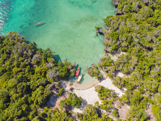 Aerial view of a beautiful tropical island and beach, small fisherman boat on clear blue reef water along Africa, Tanzania, Zanzibar. Indian Ocean