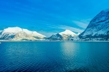 Amazing landscape of coastal scenes of huge mountain covered with snow on Hurtigruten during voyage in a blue sky