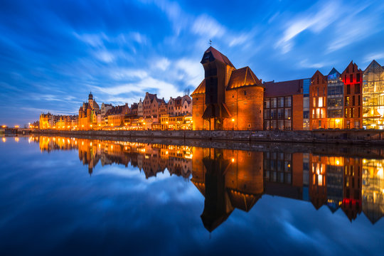 Historic port crane in Gdansk reflected in Motlawa river at dusk, Poland