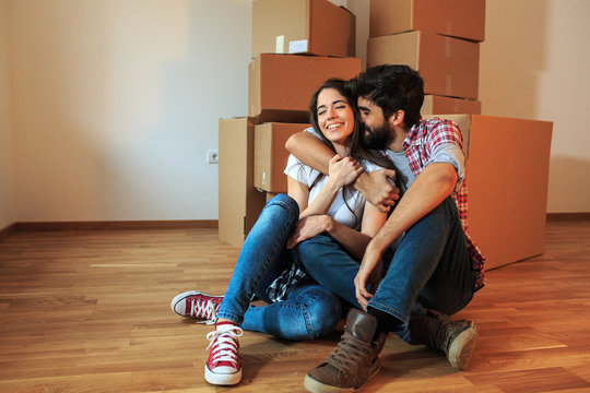 Young couple moving into a new home.They sitting on floor in empty apartment .Real estate concept.