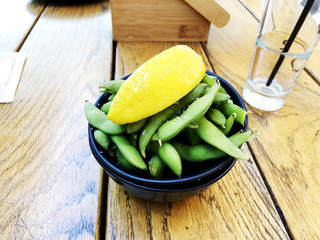 Green peas with lemon with a glass of water stand on a wooden table.