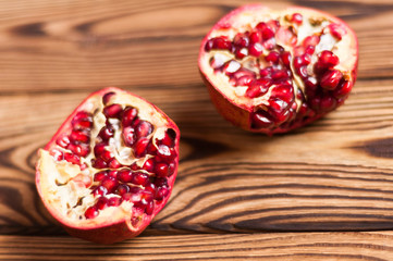 Two half red fresh ripe pomegranate with seeds on old brown weathered wooden planks