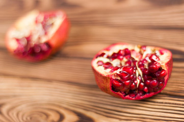 Fototapeta na wymiar Two half red fresh ripe pomegranate with seeds on old brown weathered wooden planks