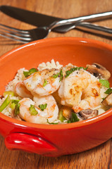 Top view, close up of sesame shrimp with almonds and cauliflower with sliced scallions, mint and mushrooms in a deep, orange, round orange, bowl- paleo diet