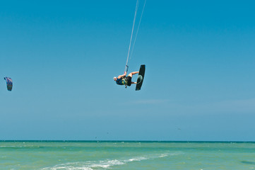 Front view of a young male, lifting out of water and spinning while kiteboarding at fast speed through rough ,tropical water of the Gulf of Mexico