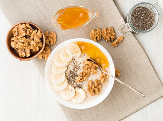 healthy breakfast - oatmeal with nuts, bananas, chia, jam,  top view, close up
