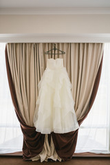 Elegant dress with hanging on window with curtains