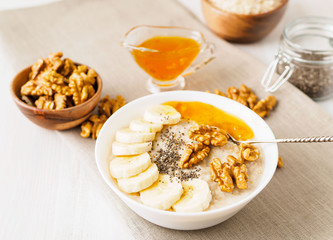 healthy breakfast - oatmeal with nuts, bananas, chia, mango jam, side view, close up