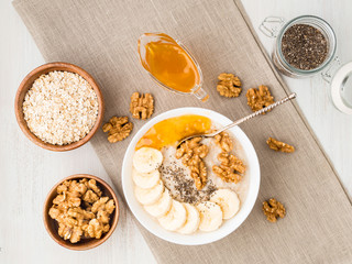 healthy breakfast - oatmeal with nuts, bananas, chia, jam,  top view, close up
