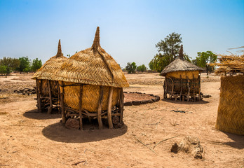 Traditional granaries made of woods and straw in an african village in Burkina Faso. They are on stilts to protect the crops against animals. - obrazy, fototapety, plakaty