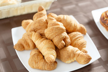 Fresh croissants on white plate. French traditional pastry. Breakfast in hotel smorgasbord.