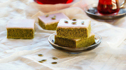 Matcha green tea cakes with white chocolate glaze seeds with tea on the white background