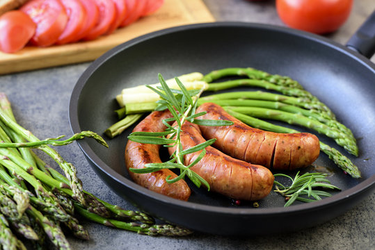 Sausages with herbs frying in a pan