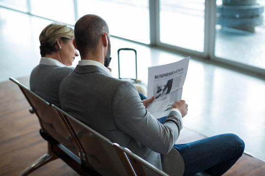 Businesspeople reading newspaper in waiting area