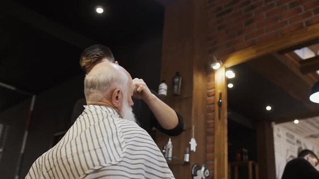 Hairdresser makes new hairstyle for senior man