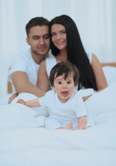 Fototapeta premium Portrait of a joyful family sitting on the bed at home