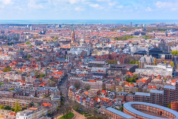 Fototapeta premium Aerial wide-angle cityscape of The Hague (Den Haag) with the North Sea and cloudy blue sky, Netherlands