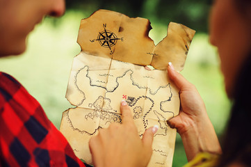 Couple of lovers holding a pirate map in hands and looking for treasures. Romantic quest journey concept. Love story