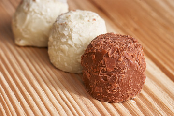 Macro. White and milk chocolate candies on a light wooden background