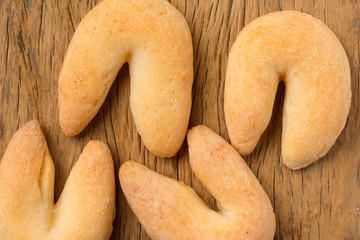 Cheese bread known as Chipa in Brazil, shaped like a horseshoe. Group of snacks on rustic wood, flat lay design.