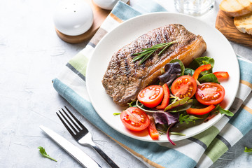 Grilled beef striploin steak with fresh salad.