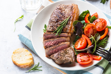 Grilled beef striploin steak with fresh salad.