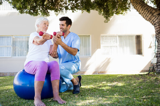Nurse helping senior woman doing exercises