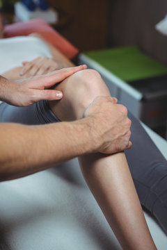 Physiotherapist giving physical therapy to the knee of a female patient