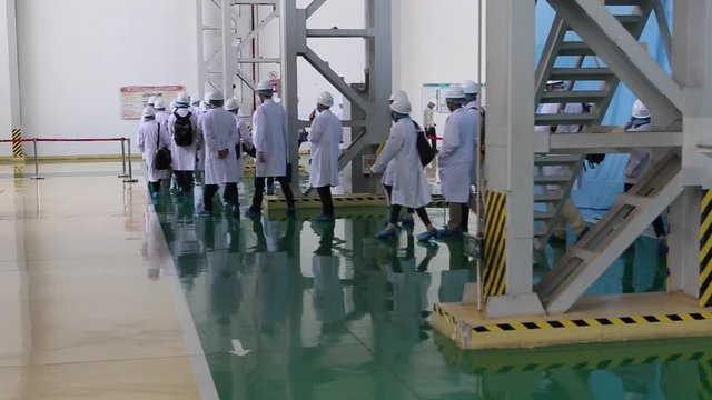 An excursion, people in White robes go through the factory workshop,transformers