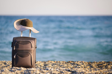 Fototapeta na wymiar suitcase and hat on beach and sea on background
