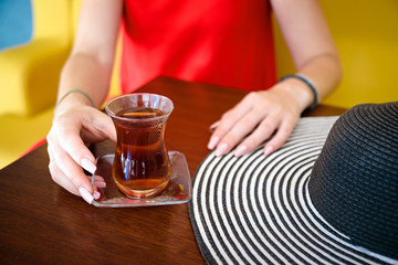 Fototapeta na wymiar women in red dress and hand with turkish tea on the wooden table and hat .
