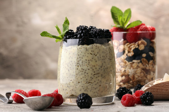 Healthy berry chia pudding in a jar with scattered fruit isolated on rustic grey background