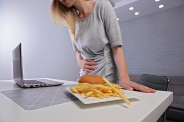 Woman having stomachache because of eating unthelthy junk food. Chronic gastritis or Ulcer.